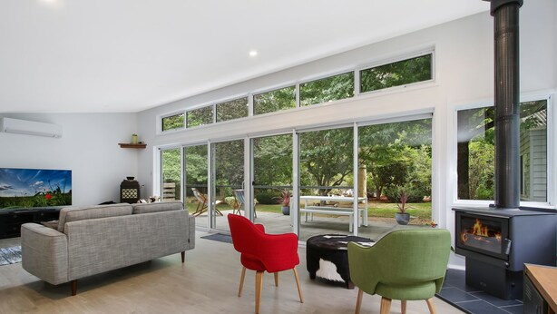 A modern living room with a large window, a fireplace, and a sofa. - Marshmallow Retreat (Bright)