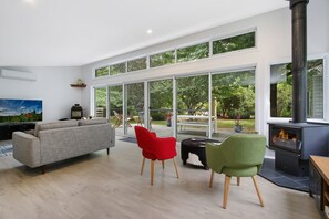 A modern living room with a large window, a fireplace, and a sofa. - Marshmallow Retreat (Bright)