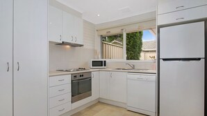 Una cocina moderna con armarios blancos, microondas, estufa, horno, lavavajillas y refrigerador.