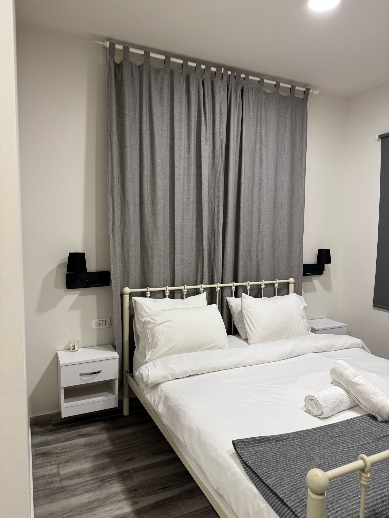 A neatly arranged bedroom with a bed, bedside tables, and a window with curtains.