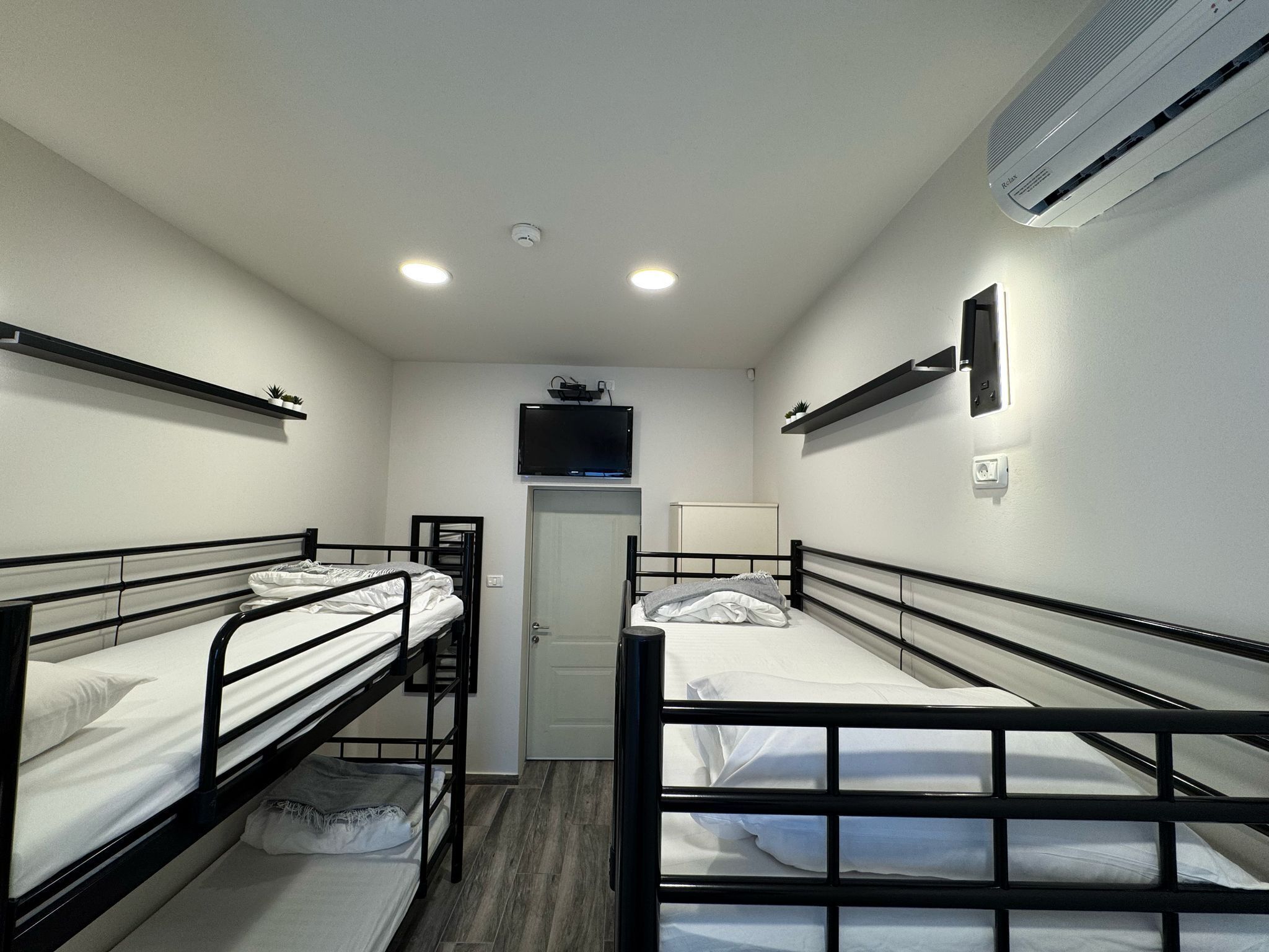 A compact room with bunk beds, a television, and an air conditioning unit.