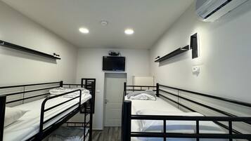 A compact room with bunk beds, a television, and an air conditioning unit.