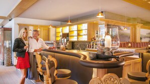 Uma área de bar com cadeiras de madeira, balcão e uma janela grande com vista.