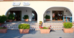 Entrada de un hotel con dos arcos, plantas en macetas y un letrero que dice "Hotel Felix".
