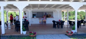 Un café al aire libre con mesas, sillas y plantas en macetas.