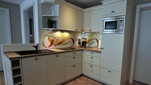 Une cuisine moderne dotée d’un four à micro-ondes encastré, d’un évier et d’un crédence décorative.