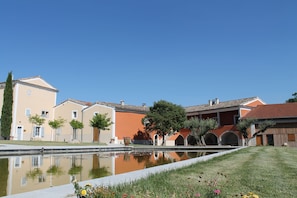Une cour avec un bassin aux eaux calmes et réfléchissantes, des bâtiments à l’architecture traditionnelle et une pelouse bien entretenue.