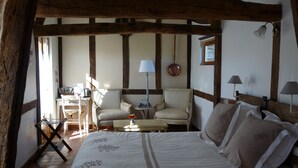 A bedroom with a large bed, two chairs, a small table, and a lamp. - B&B L'Etape Normande & SPA (Montroty)
