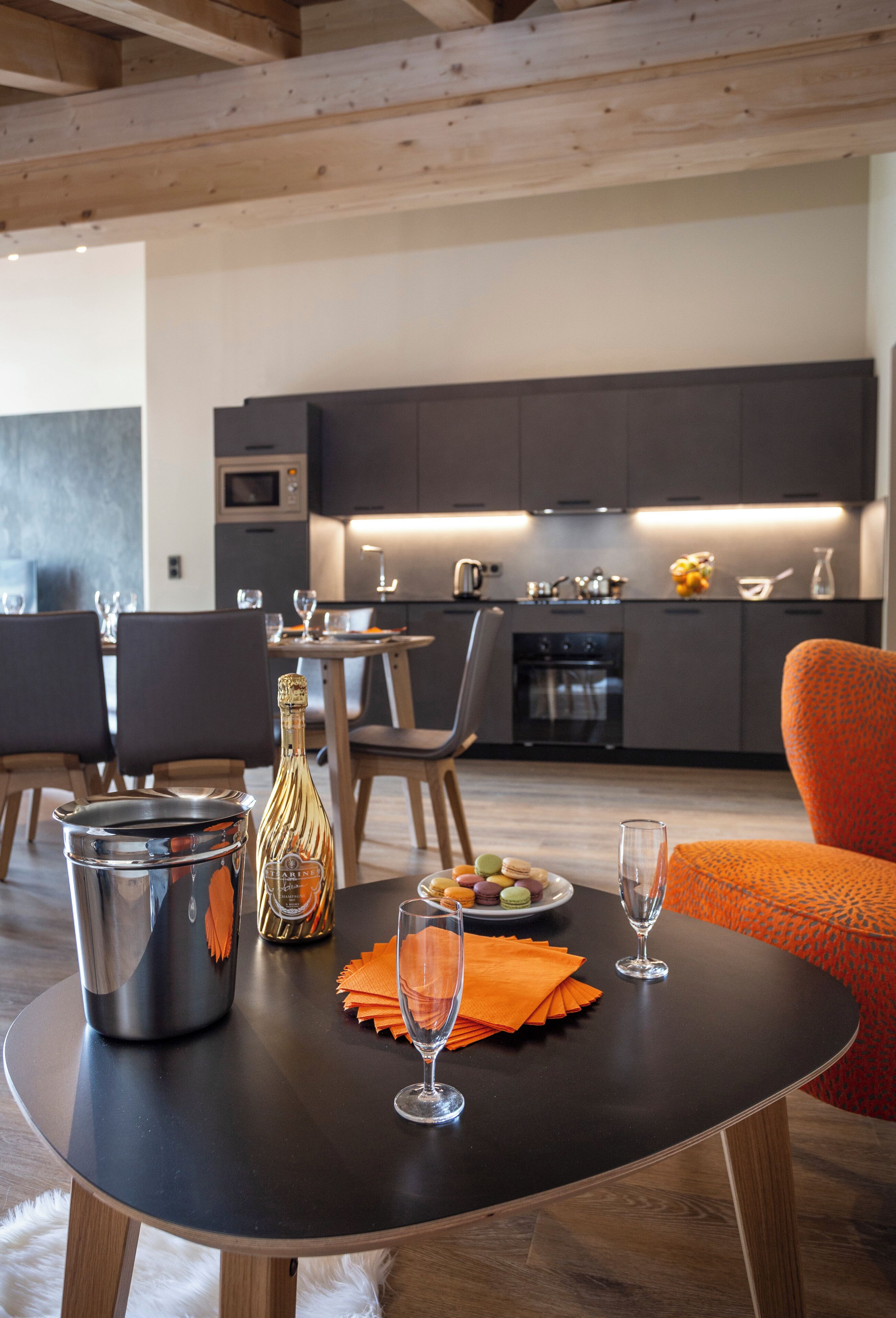 Une cuisine moderne avec des meubles de couleur sombre, un coin repas doté d’une table ronde et un espace salon.