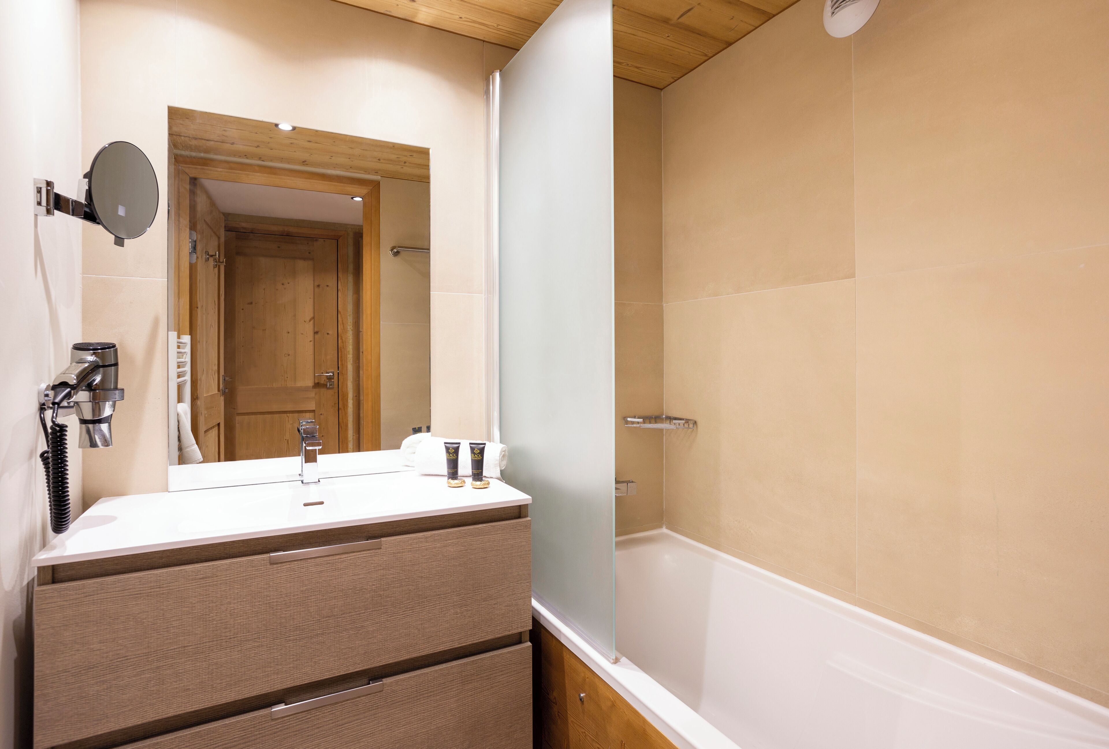 A bathroom with a wooden vanity, a mirror, a towel rack, and a bathtub.