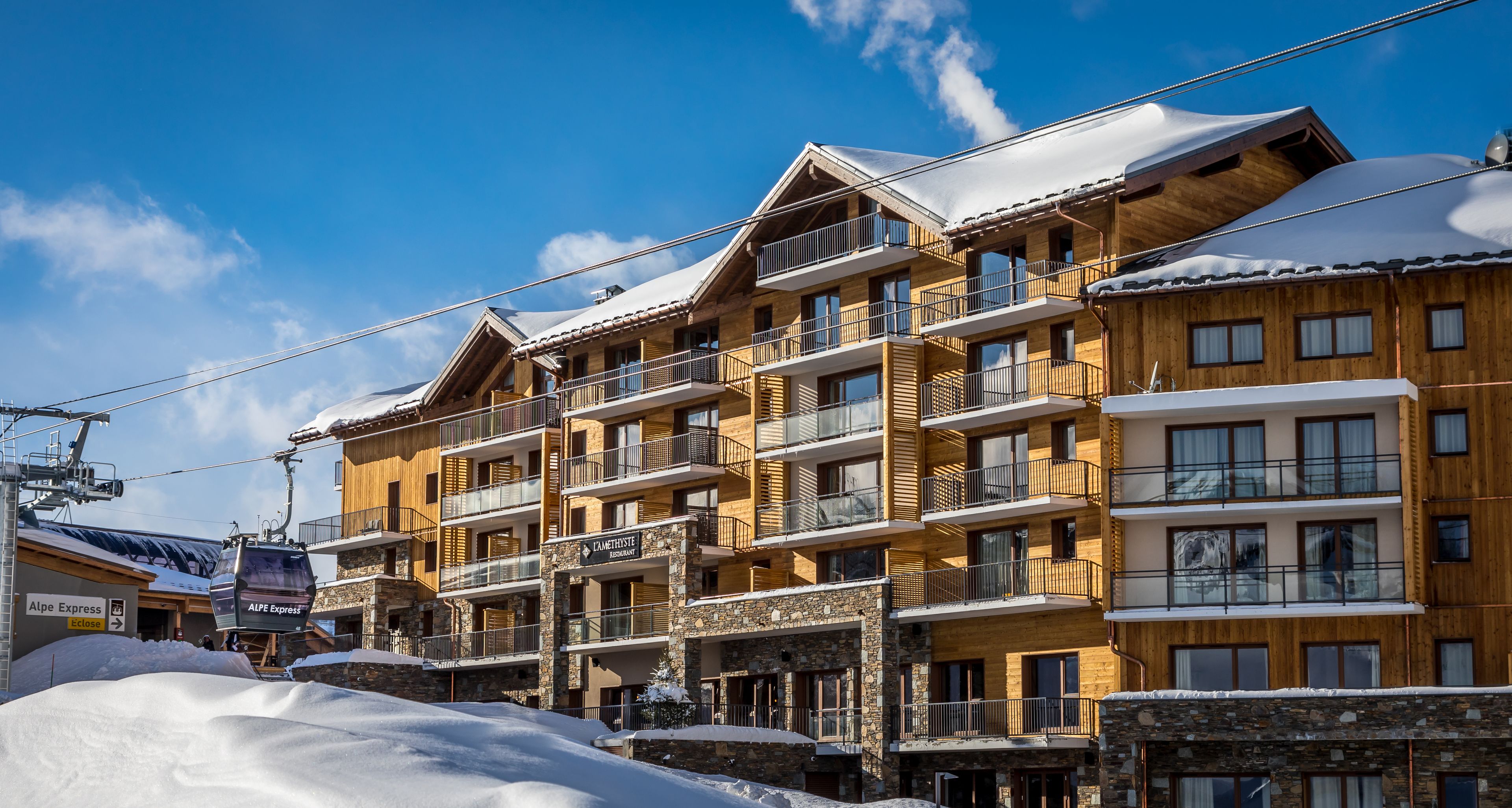 A multi-story hotel with balconies, ski lift cables, and snow-covered roofs.