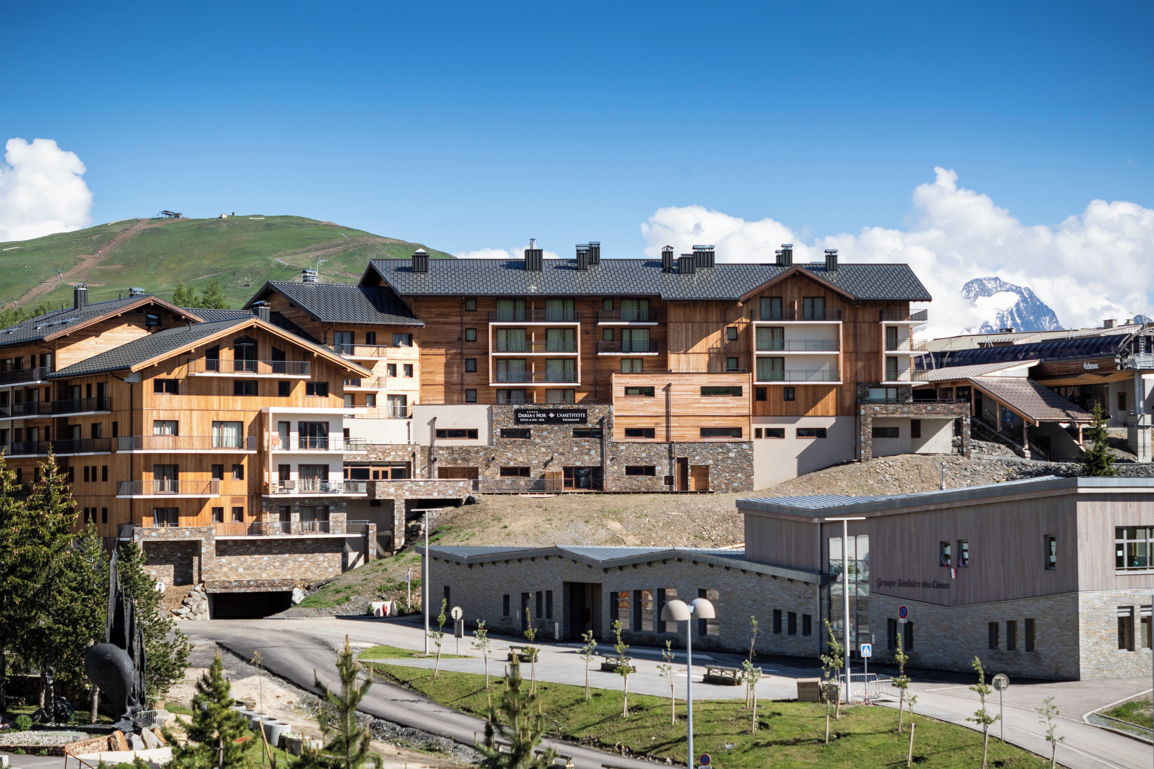 Et moderne hotel med flere bygninger, en skilift og et bjerg i baggrunden.