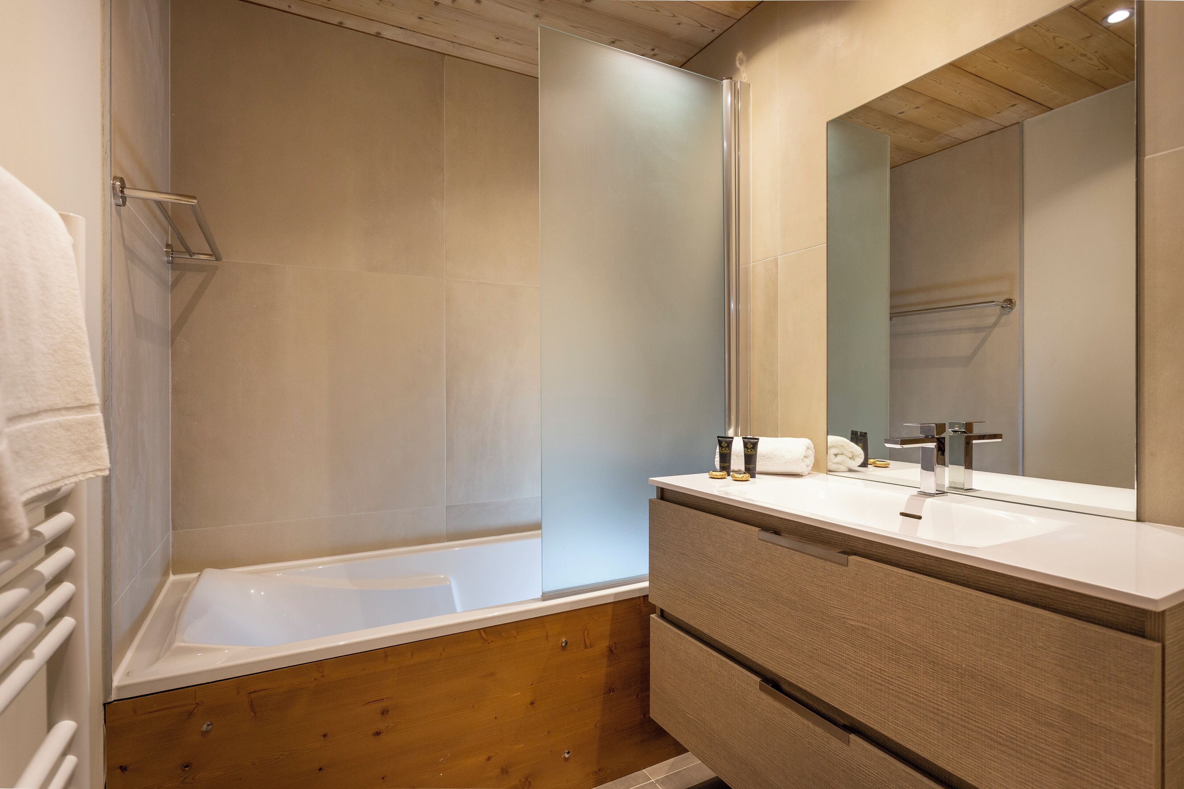 A modern bathroom with a bathtub, a vanity with a mirror, and a towel rack.