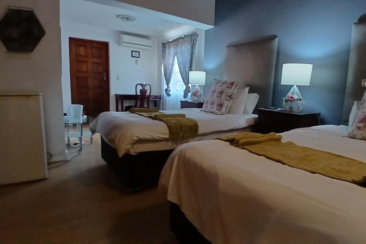 Hotellihuone, jossa on kaksi sänkyä, työpöytä, tuoli ja yöpöytä, jossa on lamput.
