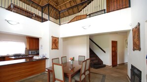 Un comedor amplio con una mesa y sillas de madera, una cocina con microondas y una escalera que sube a un nivel superior.