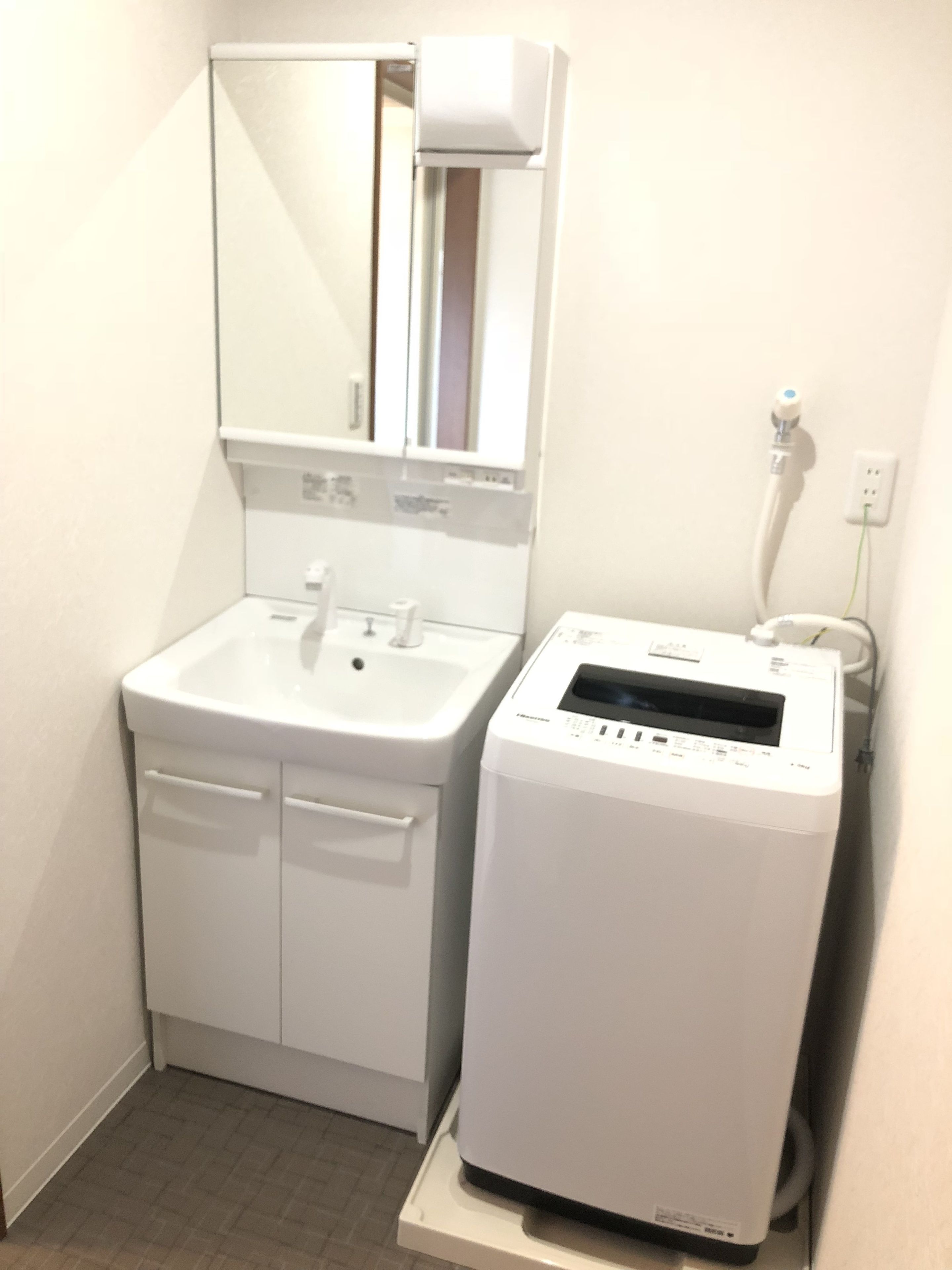 Een badkamer met een wit wastafel, spiegel en een witte draagbare verwarming.