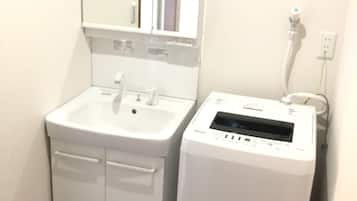 Een badkamer met een wit wastafel, spiegel en een witte draagbare verwarming.
