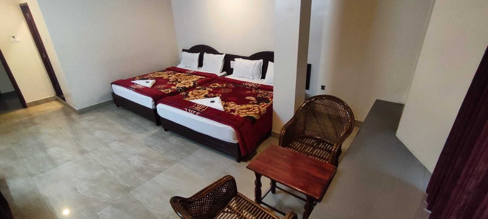 A hotel room with two beds, a wooden chair, and a small table.