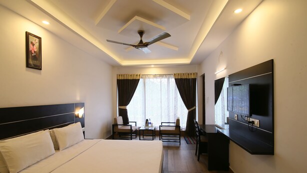 A hotel room with a bed, a desk, a chair, a television, and a ceiling fan.