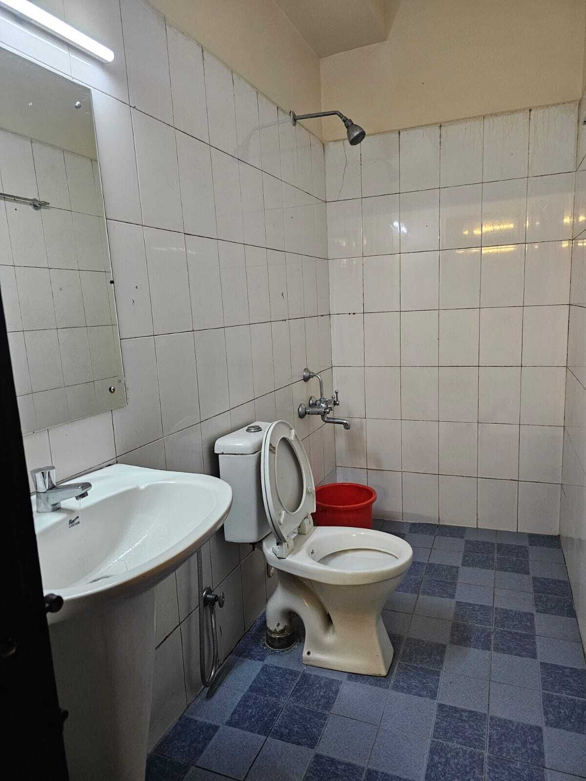 Un baño pequeño con azulejos blancos, un lavamanos, un inodoro y una ducha.
