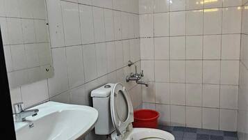 Un baño pequeño con azulejos blancos, un lavamanos, un inodoro y una ducha.