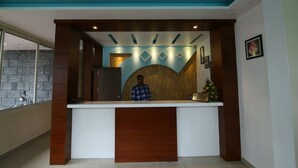 A reception desk with a modern design, a person standing behind it, and a framed picture on the wall.