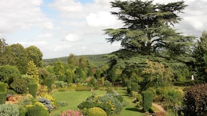 A well-maintained garden with various types of trees and shrubs, a clear pathway, and a distant view of hills. - Le Prieure d'Orchaise (Valencisse)
