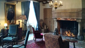 A traditional room with a fireplace, wooden furniture, and a large painting. - Le Prieure d'Orchaise (Valencisse)