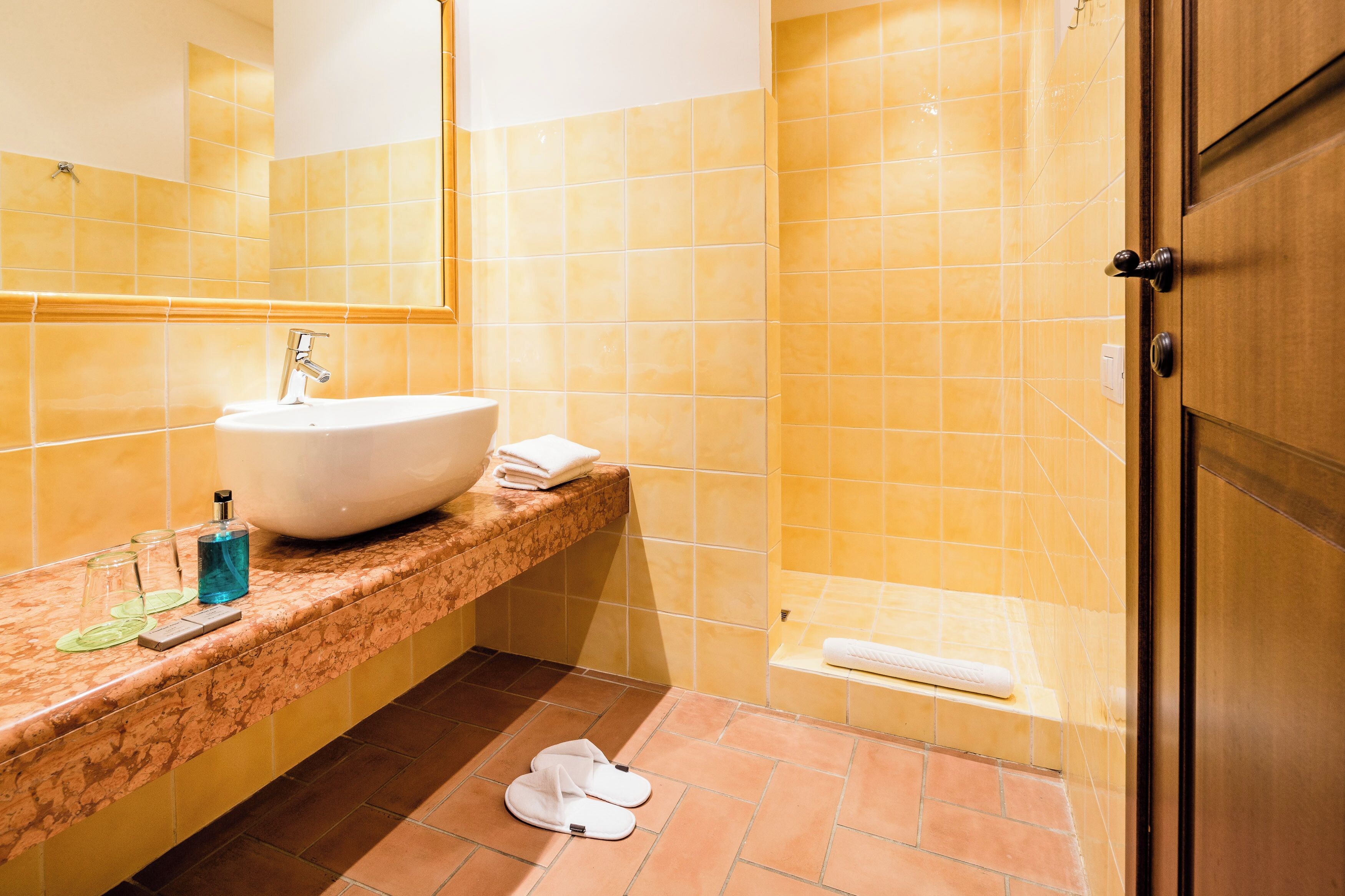 A bathroom with a sink, mirror, and shower.
