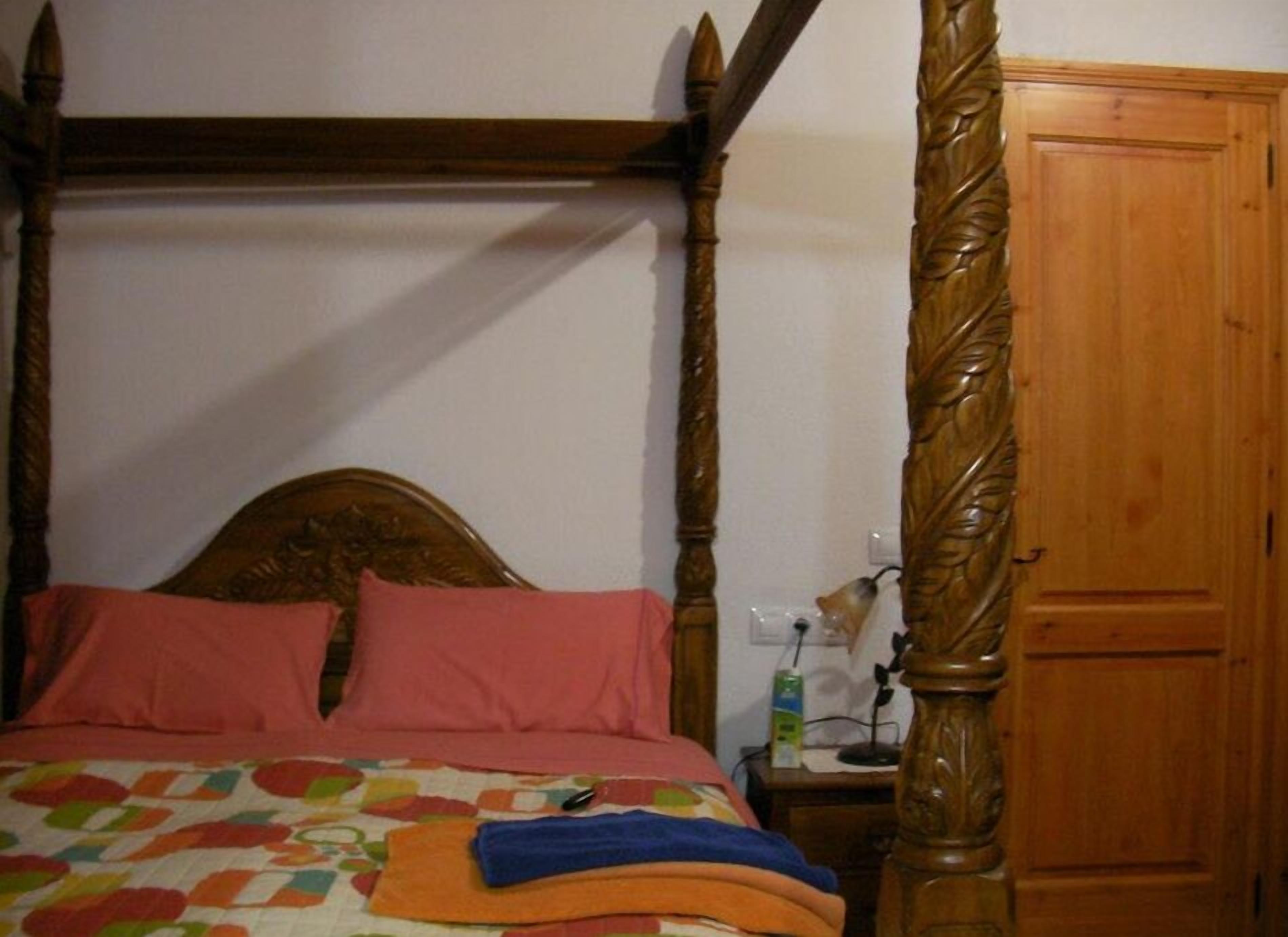 Una cama con dosel y colcha estampada con motivos florales, con almohadones rosados.