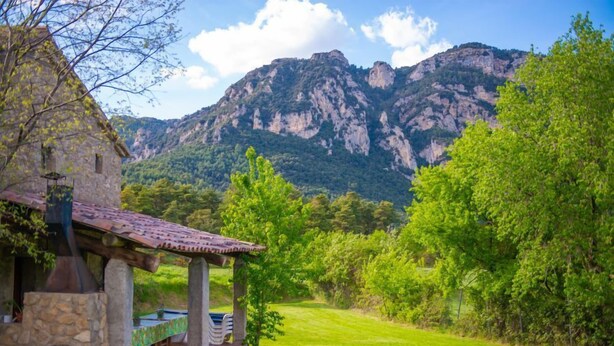 Un edificio de piedra con tejado de tejas y un área de estar cubierta al aire libre.