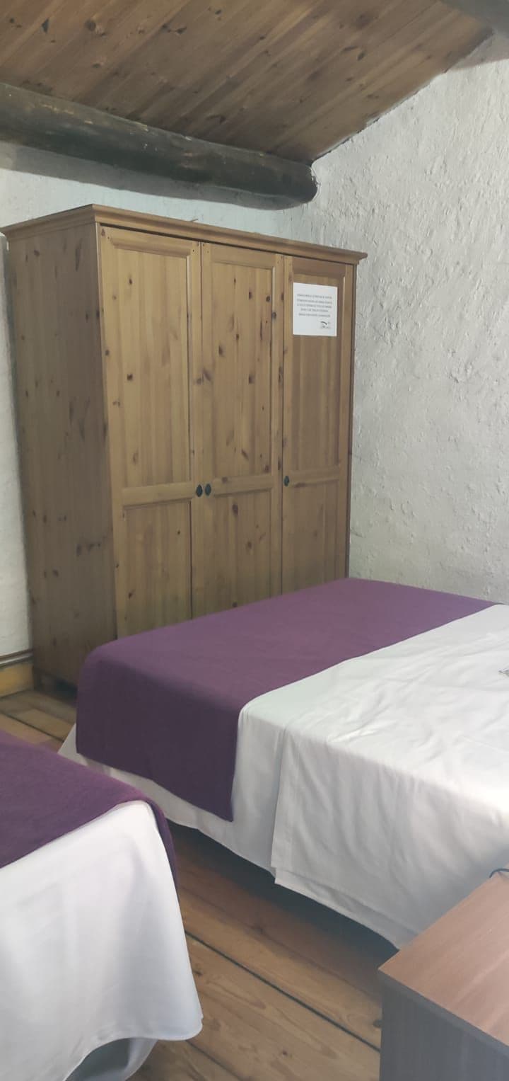 Une chambre avec deux lits, une armoire en bois et un mur blanc.