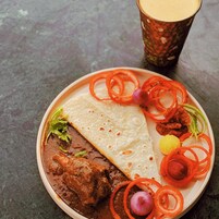 Um prato com carne, pão sírio e legumes fatiados.