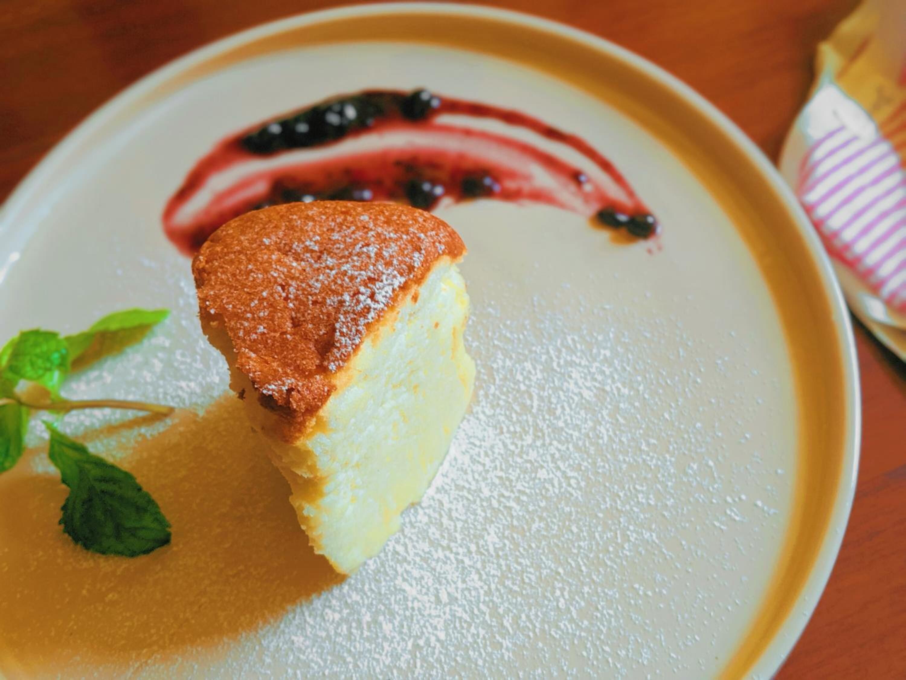 Un dessert su un piatto con una spolverata di zucchero a velo e salsa di frutti di bosco.