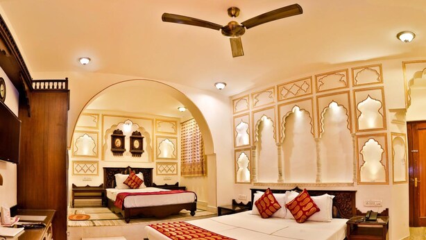Um quarto de hotel espaçoso com duas camas, um espaço para sentar e uma escrivaninha.