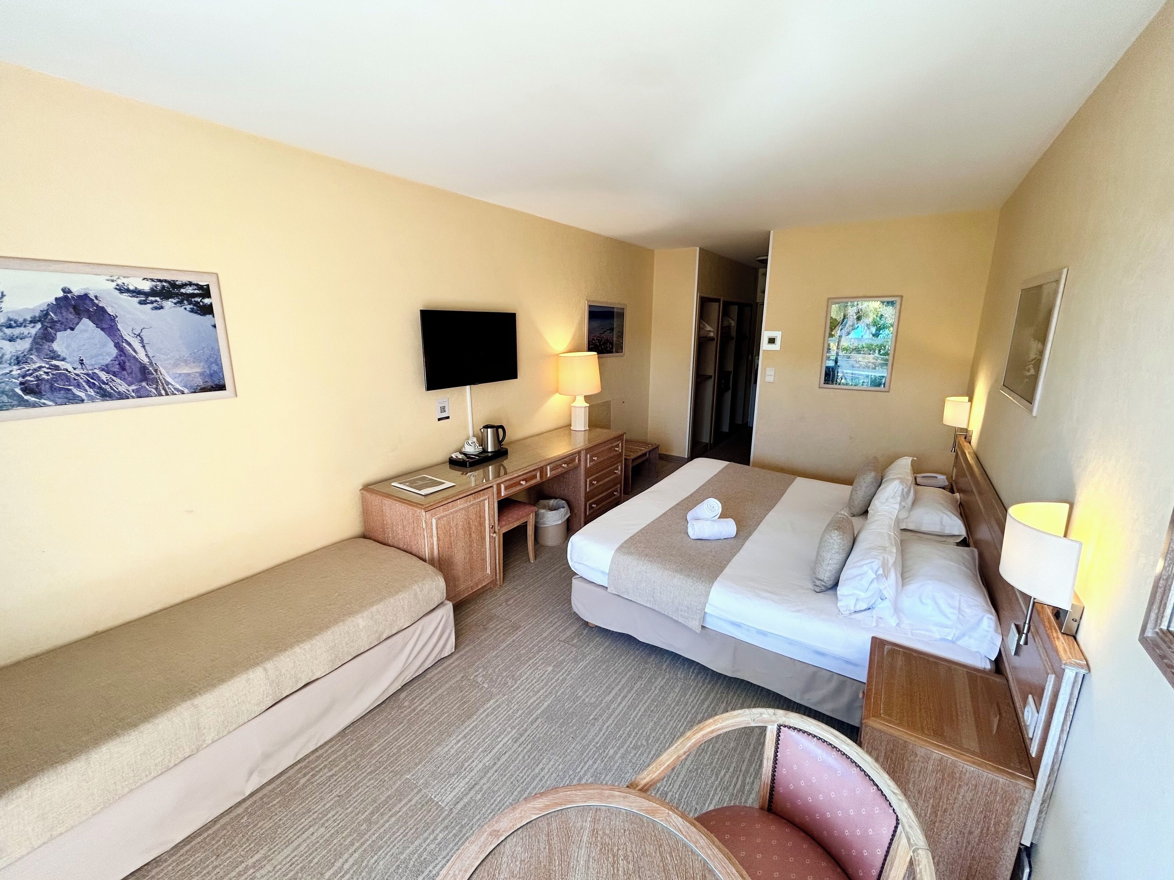 A hotel room with a bed, a desk, a chair, a television, and a picture on the wall.