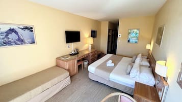 A hotel room with a bed, a desk, a chair, a television, and a picture on the wall.