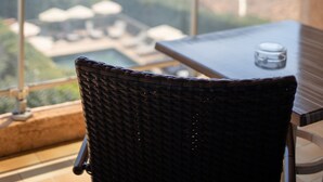 A wicker chair and a table on a balcony overlooking a scenic view of the sea and greenery. - Hôtel La Pinède (Ajaccio)
