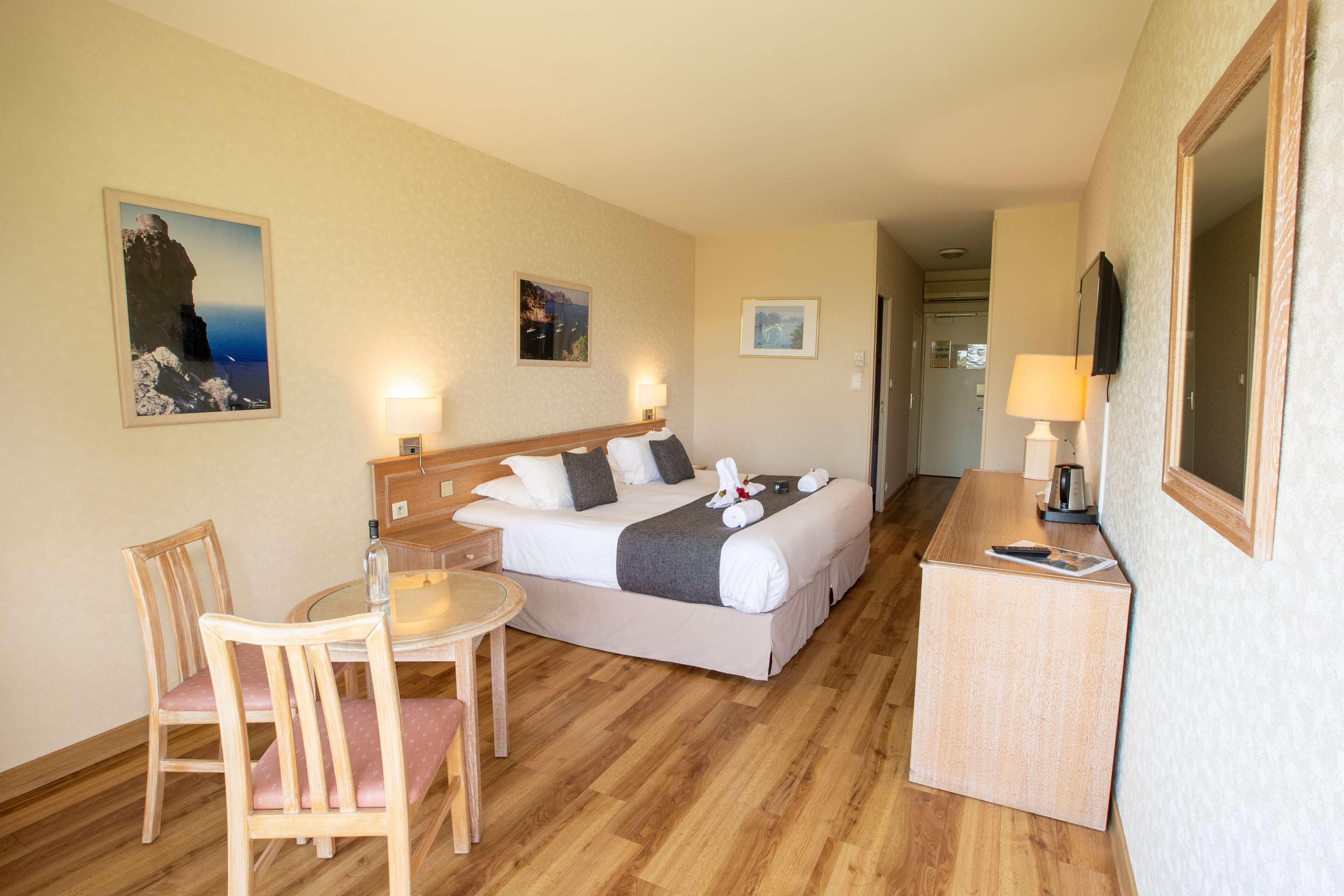 Une chambre d’hôtel comprenant un lit, une table de chevet, une chaise et un bureau avec une lampe.