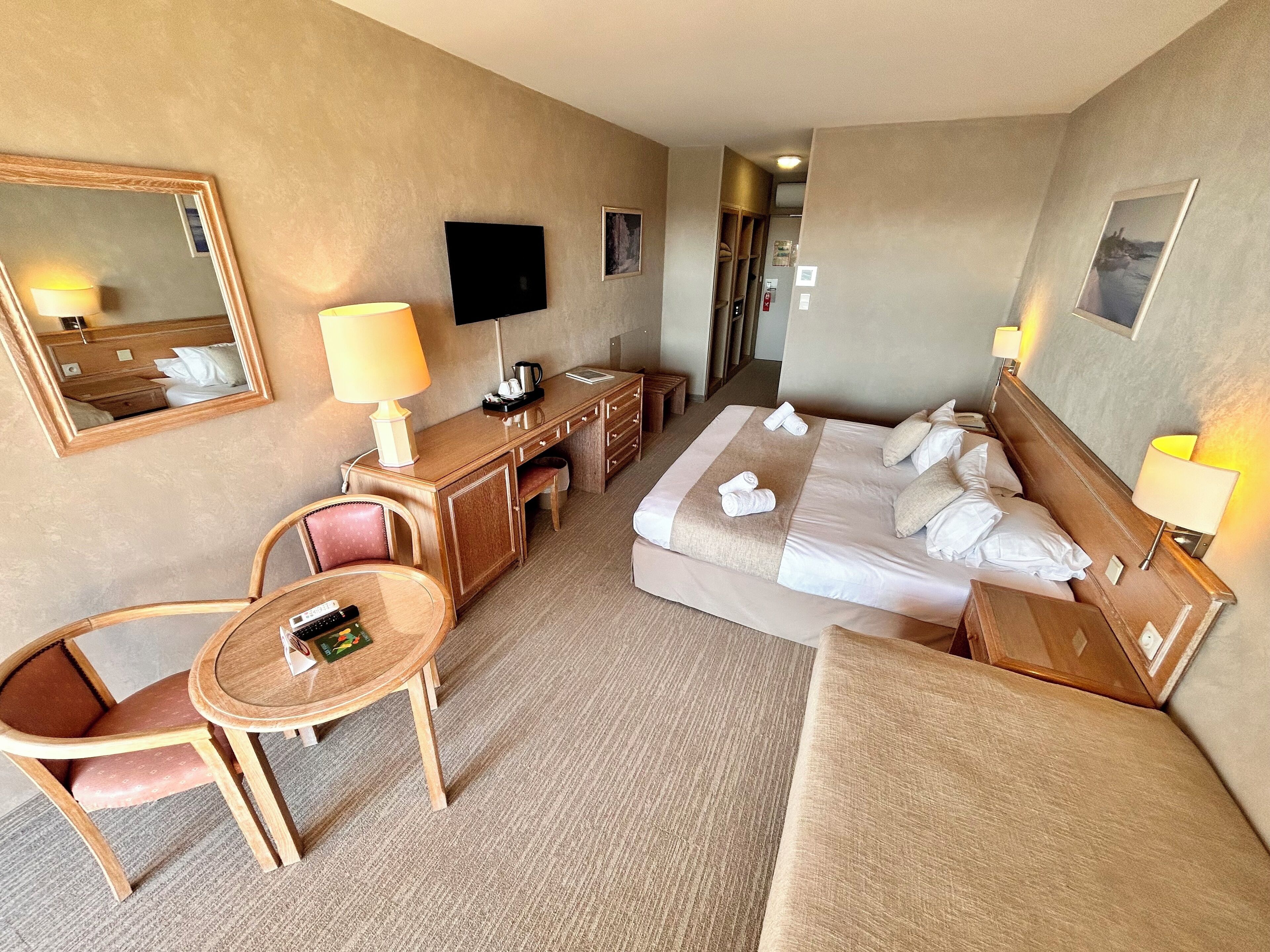 Une chambre d’hôtel comprenant un lit, des tables de chevet, un bureau, une chaise, une télévision et un miroir.