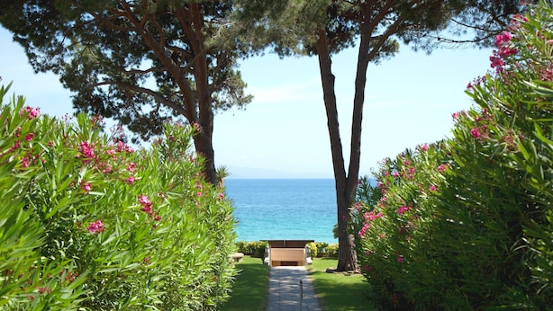 A pathway leading to a seating area with a view of the sea. - Hôtel La Pinède (Ajaccio)