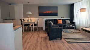 A modern living room with a sofa, coffee table, and dining area.