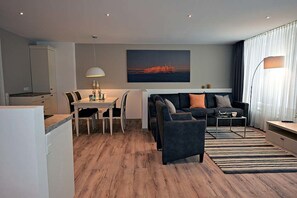 Een moderne woonkamer met een bank, salontafel en eethoek.