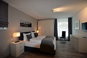 Een moderne hotelkamer met een groot bed, nachtkastjes, een kledingkast, een bureau en een stoel.