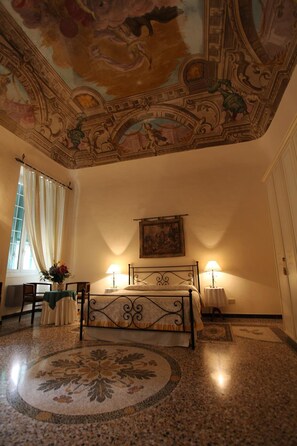 A bedroom with a bed, two bedside lamps, a painting on the wall, and a decorative ceiling. - B&B Ca' del Vescovo (Imperia)