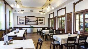 A dining area with multiple tables and chairs, wooden paneling, and framed photographs on the walls. - Hotel Pansky dum (Blovice)
