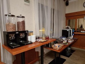 A buffet setup with food dispensers, a coffee machine, and a refrigerator.
