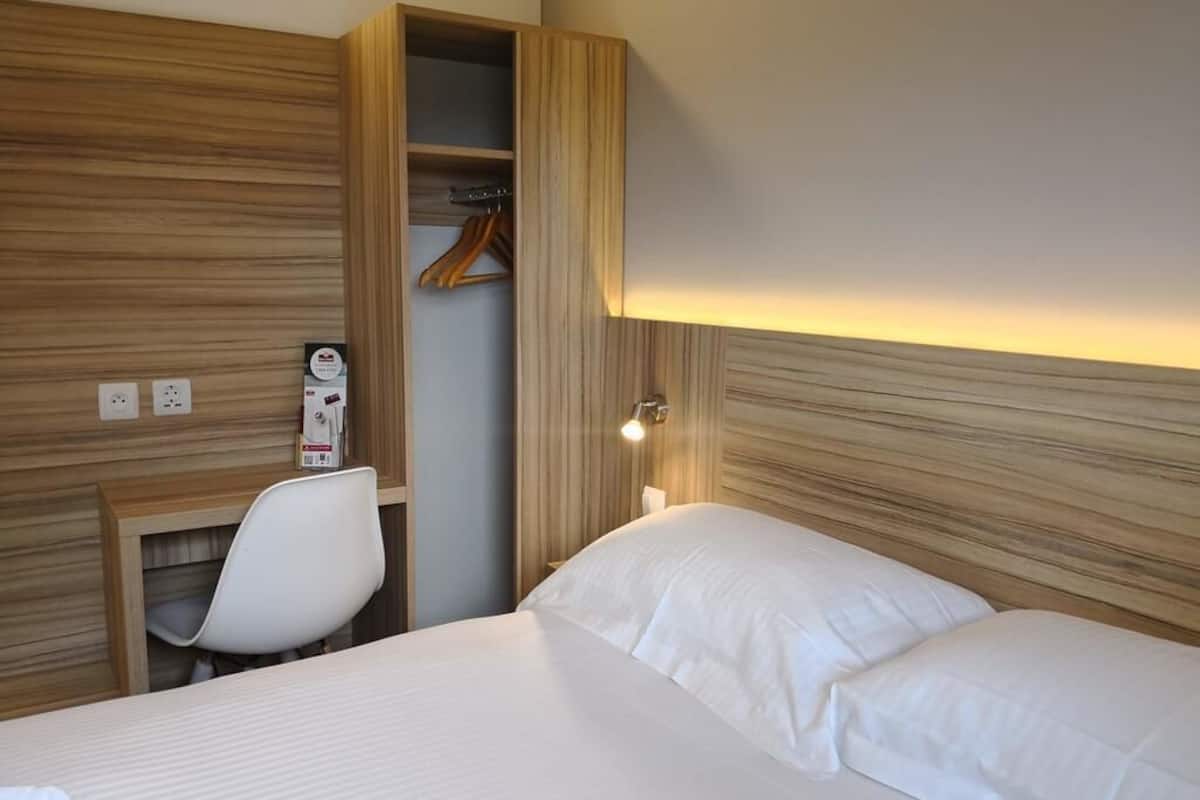 Ein Hotelzimmer mit Bett, Schreibtisch und Kleiderschrank.