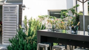 An outdoor seating area with a table and stools, a red umbrella, and a building with a 'Best Hotel' sign. - Best Hotel Bordeaux Sud (Villenave-d'Ornon)