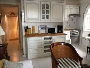 A compact kitchen with white cabinetry, a microwave, a coffee maker, and a stove.